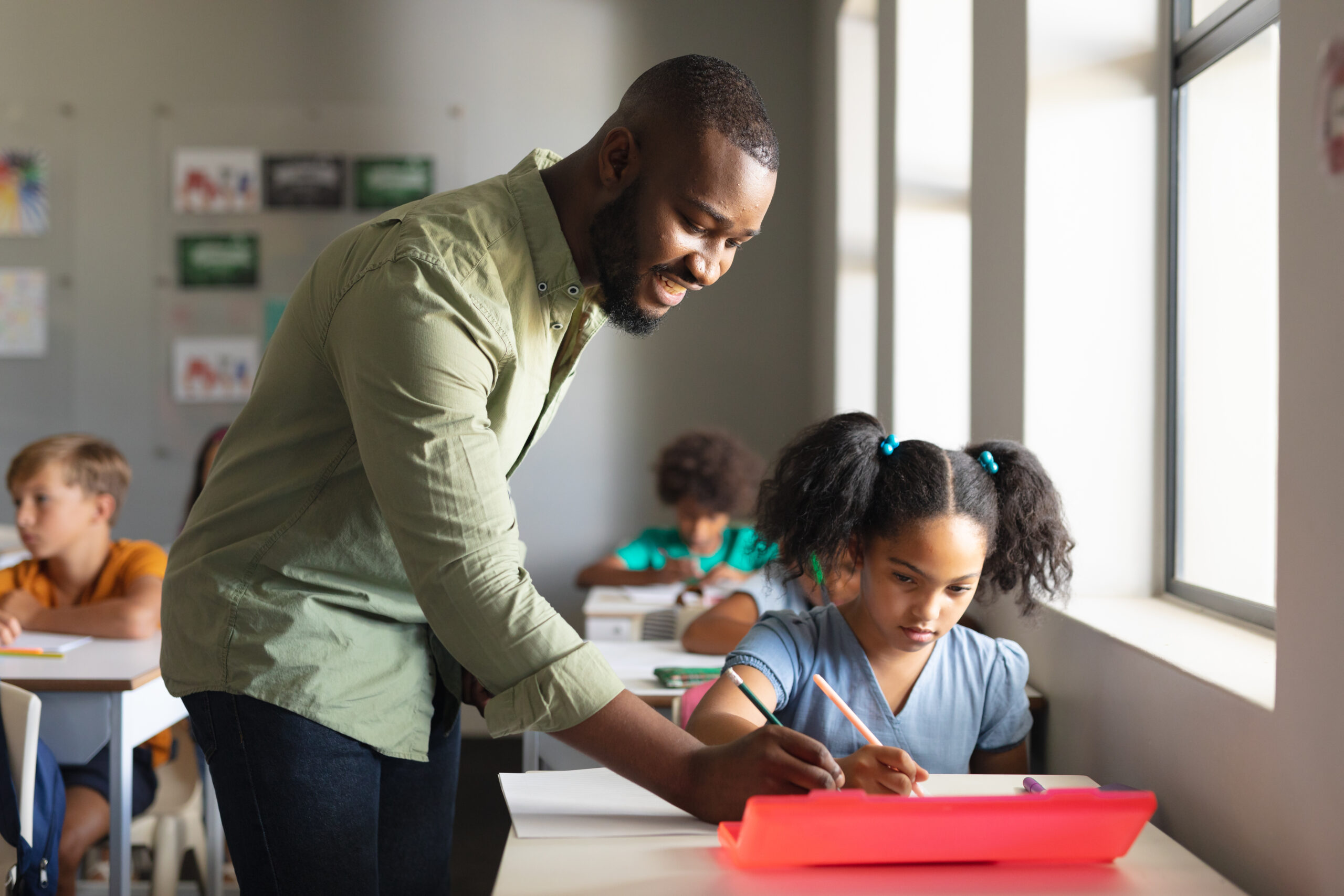 Black man assisting elementary school student in classroom